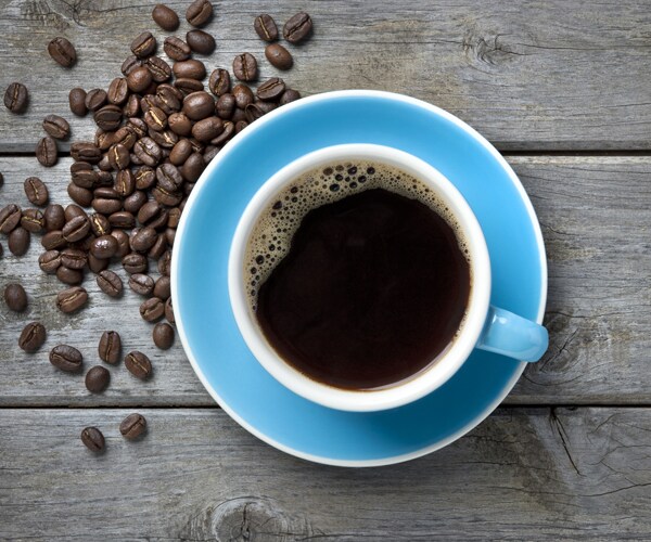 a cup of coffee surrounded by coffee beans