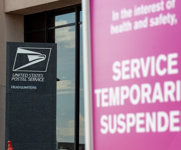 postal service sign with a pink sign saying suspended