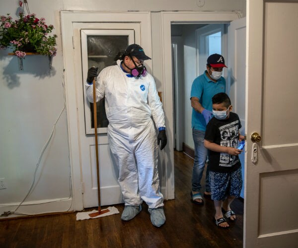 a man is shown in mask, and other protective gear as he prepares to do work in a home with a man and his son