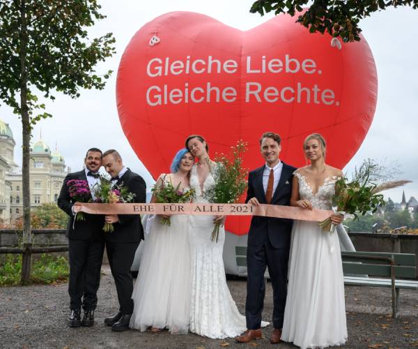 two men two women and a man and woman celebrate their weddings in front of a giant heart balloon
