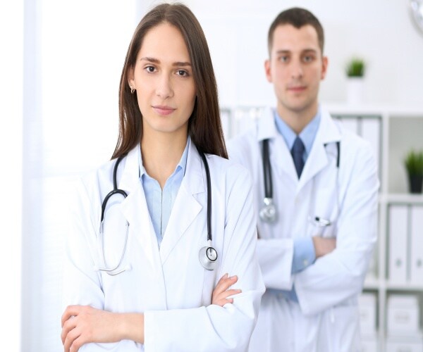 A female physician in front, male physician behind her