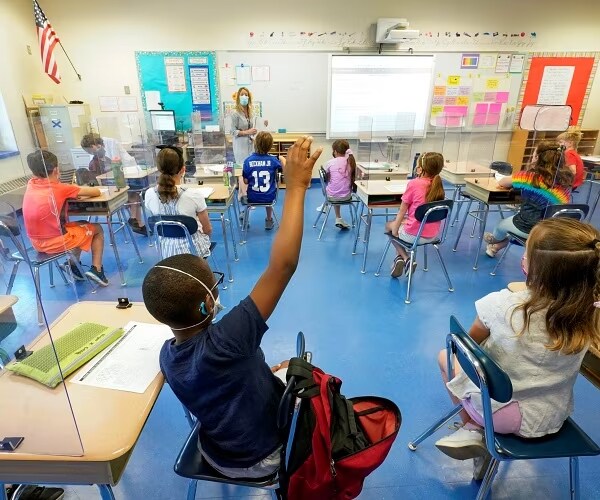 child raises hand in a classroom