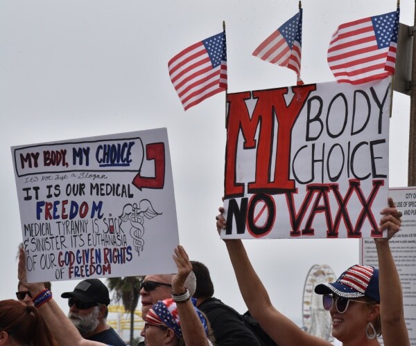 protesters against mandatory vaccine legislation hold my body my choice and medical freedom signs