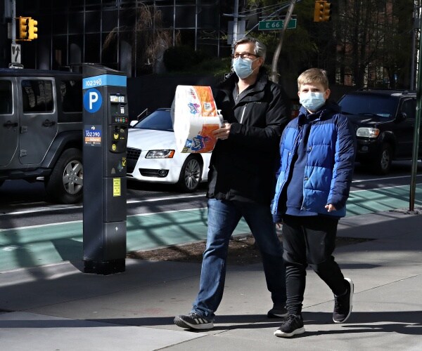 man and son wearing masks and jackets walking outside
