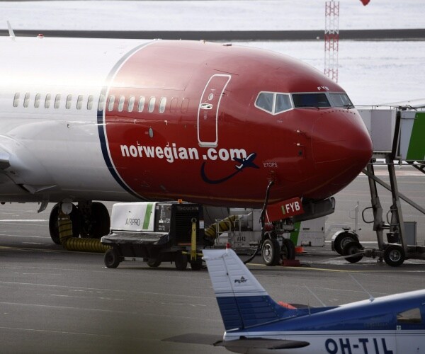 boeing 737 model norwgian airlines plane in red and white is shown on the tarmac