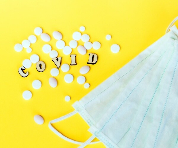 surgical masks, covid spelled out and two different types of pills