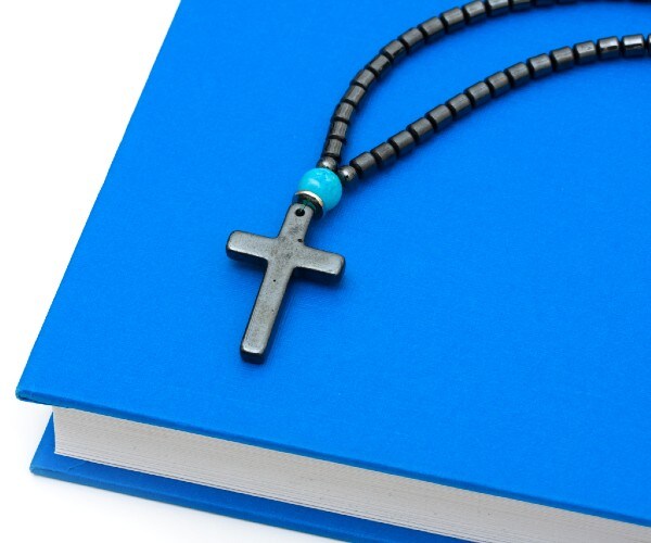 a schoolbook with a rosary on top