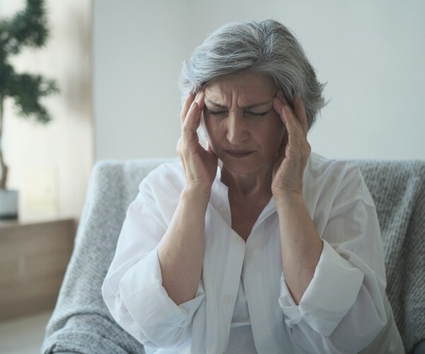 woman holding her head with headache, brain fog from long COVID