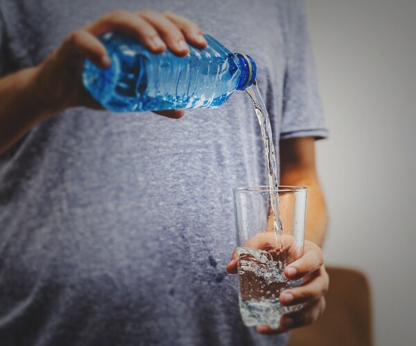 man pours water into glass