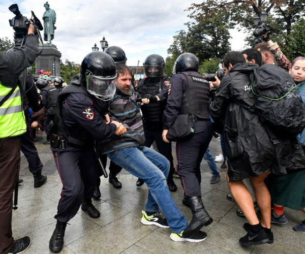 police in riot gear drag a protester