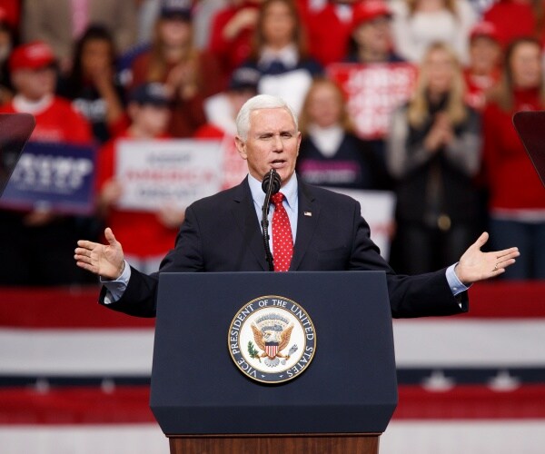 pence in a suit and red tie speaks at a rally