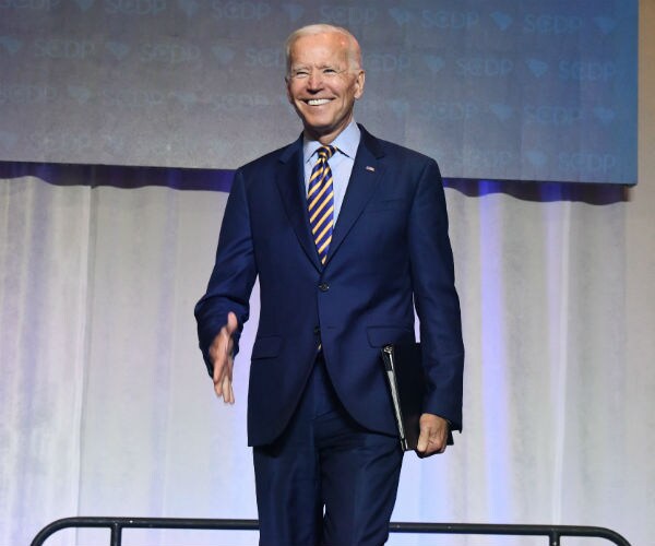 joe biden, in a blue suit, white dress shirt and stripped tie, arrives at the south carolina democratic party convention