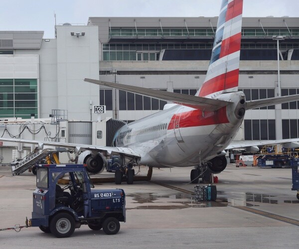 Workers prepare an American Airlines plane at a gate 