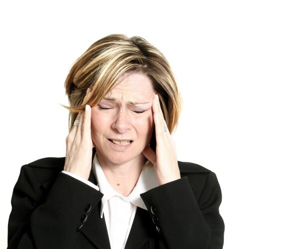 woman in suit holding head, suffering from migraine