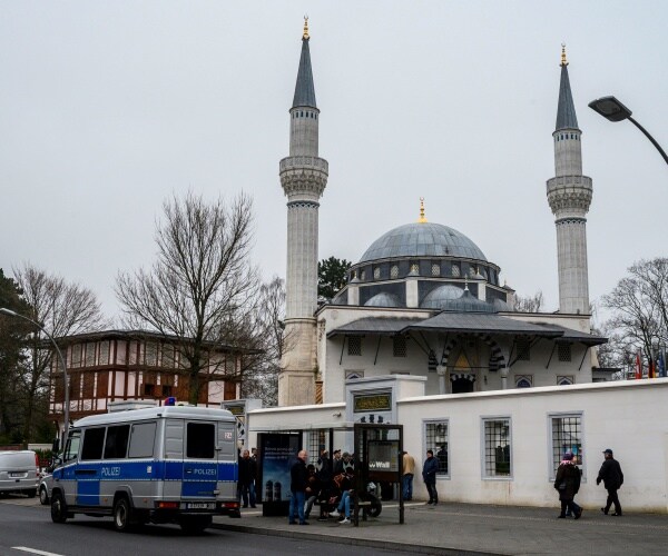 police car outside a mosque in germany with people waiting for a bus