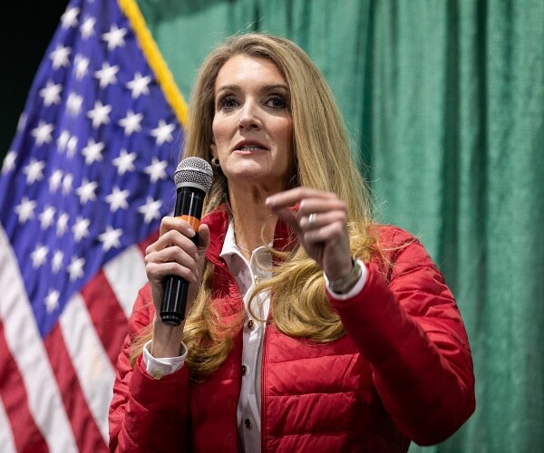 kelly loefler stands onstage with microphone