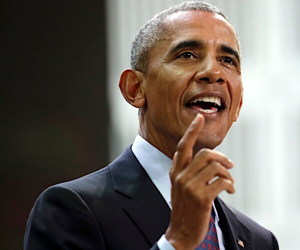 barack obama points up and smiles while speaking to the media