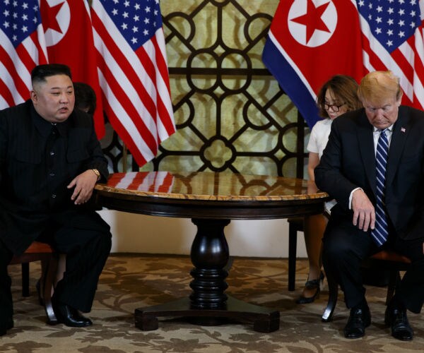 President Donald Trump in dark suit, dress shirt and blue stripped tie meets North Korean leader Kim Jong Un