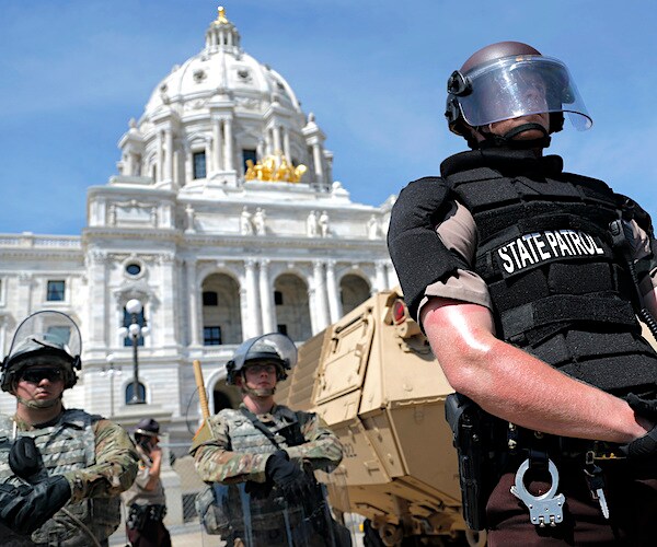 a state police officer stands before a national guard crew to protect the capitol