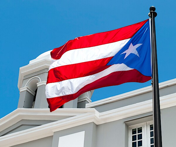 the puerto rico flag waves above a white government building