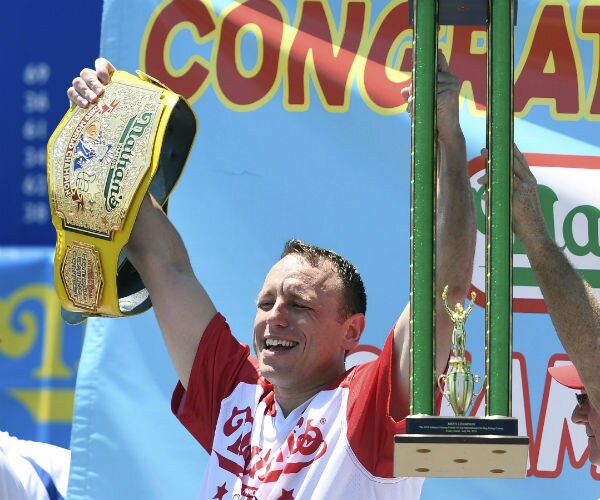 joey chestnut raises a belt and trophy