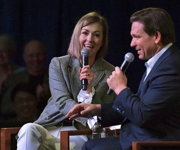 Ron DeSantis and Kim Reynolds speak into microphones