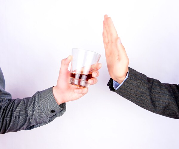 a person saying no to a glass of alcohol