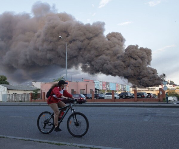 a woman riding a bicycle drives past a cloud of smoke