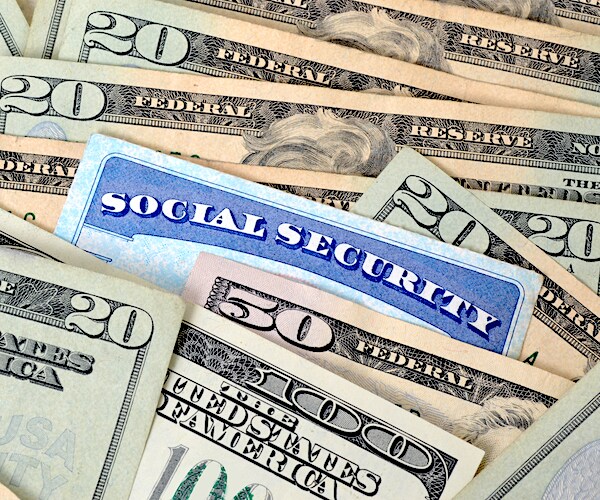 a social security card is fitted between a stack of fifthy and twenty dollar bills
