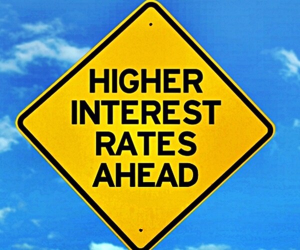 roadsign of higher interest rates ahead against blue sky 