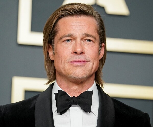 brad pitt stands on red carpet