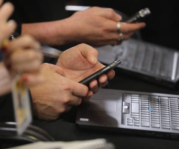 generic photo of reporter with phone and laptop