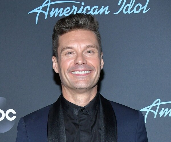 ryan seacrest stands on red carpet