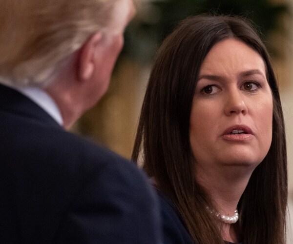 sanders in a pearl necklace looks at trump