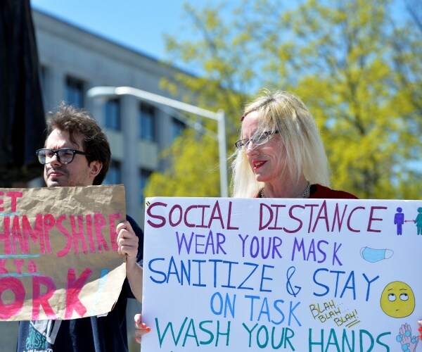 people hold up signs outside in protest of the coronavirus lockdowns