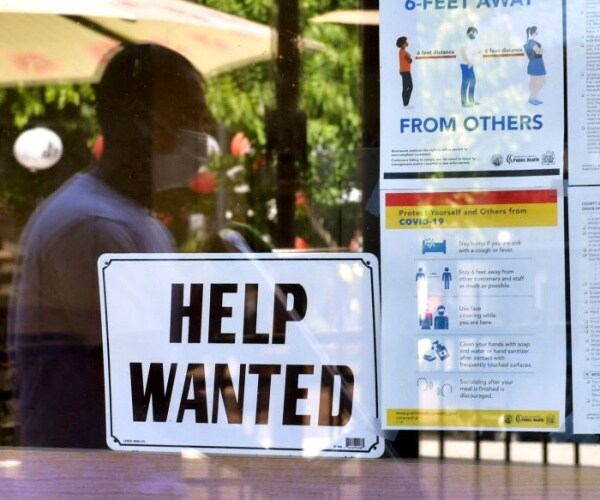 A 'Help Wanted' sign is posted beside Coronavirus safety guidelines in front of a restaurant.