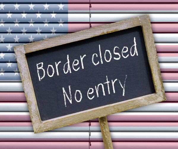 american flag on window blinds with border closed no entry sign in front