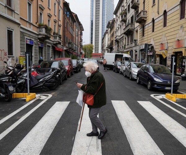 elderly italian woman wearing a mask and crossing a street