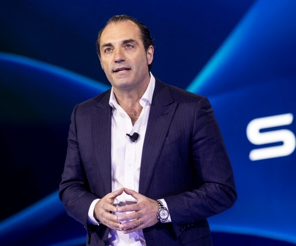 a man stands on stage speaking to an audience