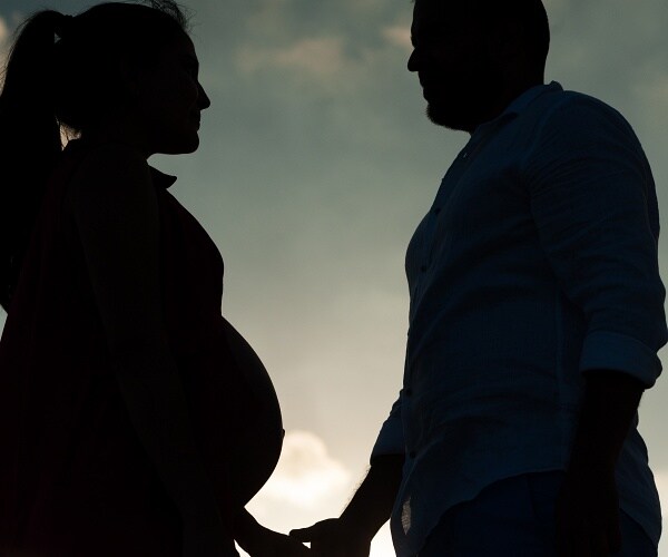 pregnant woman holding hands with man