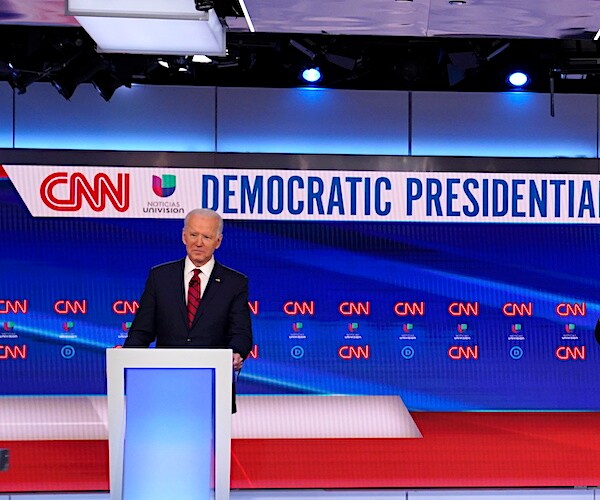 joe biden stands on a debate stage all alone