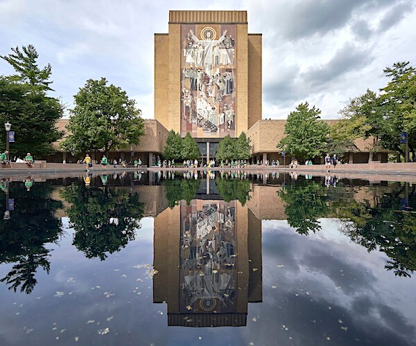 touchdown jesus reflects in the pool in front of it on the campus of notre dame