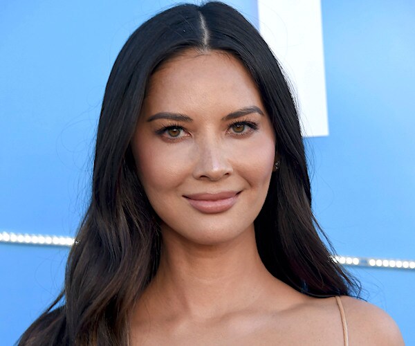 olivia munn smiles and stands on the red carpet