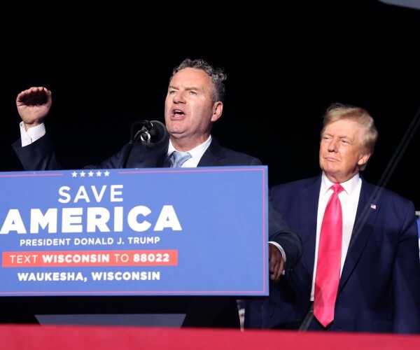 donald trump listens while tim michels speaks
