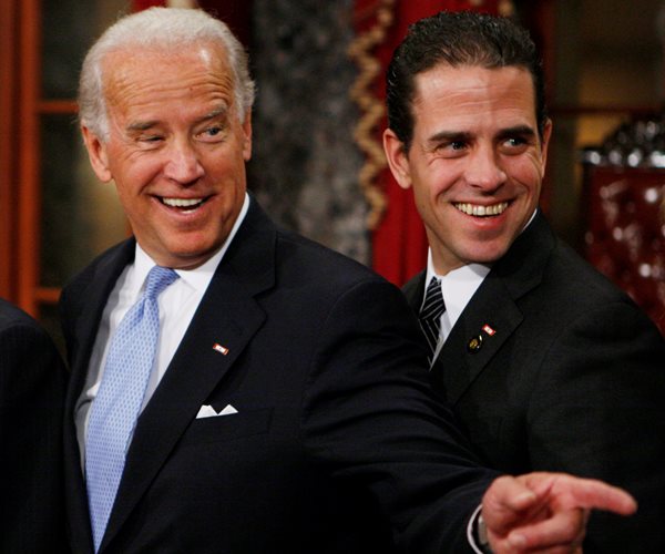 the bidens wearing black suits and smiling with joe biden in a light blue tie