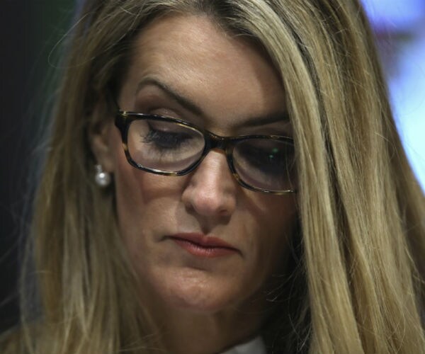 Sen. Kelly Loeffler, wearing glasses and head tilted down, listens during a virtual senate committee hearing