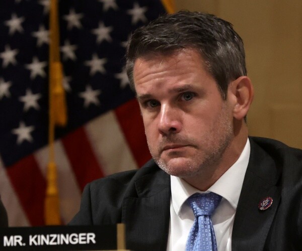 adam kinzinger listens at a meeting