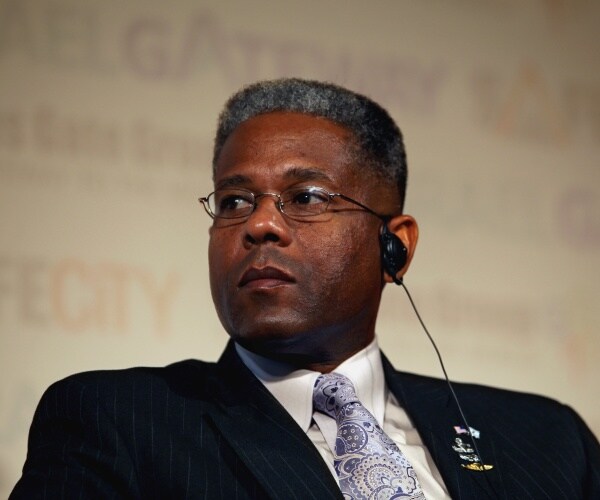 west in a black suit and purple paisley printed tie