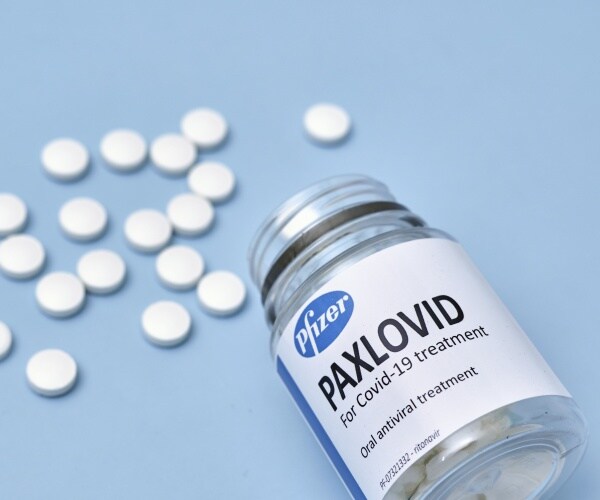 Bottle of Pfizer's COVID-19 Antiviral Pills Paxlovid, with some pills spilled out on the table