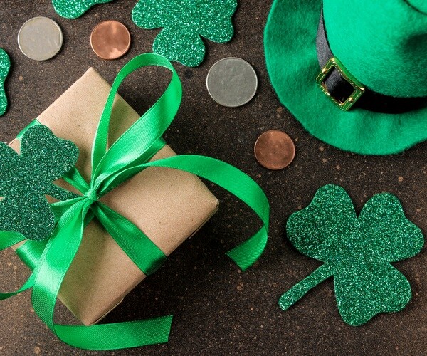 St.Patrick `s Day. celebration. Green leprechaun hat, money and clover leaf and gift box on brown background. top view